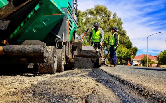 Road workers lay asphalt on a