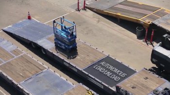 A scissor lift lots itself onto a truck at a United Rentals lawn utilizing independent technology developed by 5D Robotics.