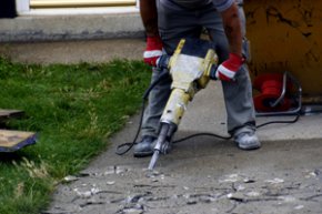 A worker utilizing a jackhammer for pavement reduction.