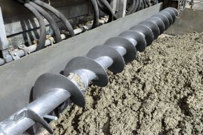 whenever using smaller slipform pavers a spreader auger spreads the concrete prior to the front metering screed,  behind that the concrete profile is made